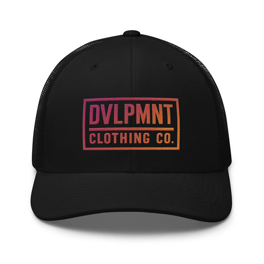 Black trucker cap with sunset embroidery design by DVLPMNT CLOTHING CO., featuring a classic mesh back and structured front panel.